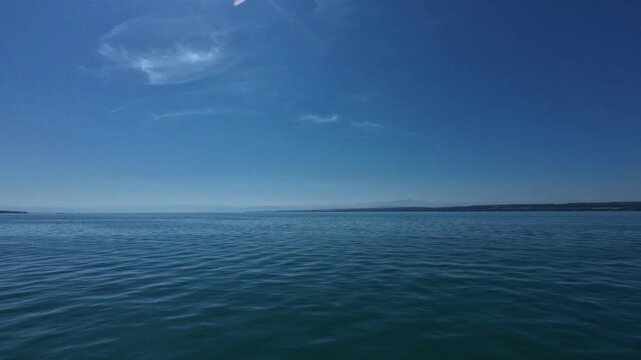 Scenic views of Lake Constance from a ferry between Konstanz and Meersburg, Germany, featuring blue water, distant shoreline, clear sky and peaceful summer landscape.