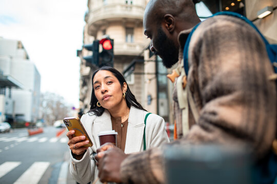 Two people using smartphone at city crosswalk