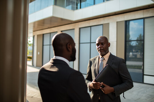 Two business professionals talking outside modern office building