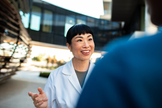 Smiling female doctor talking with colleague outside hospital