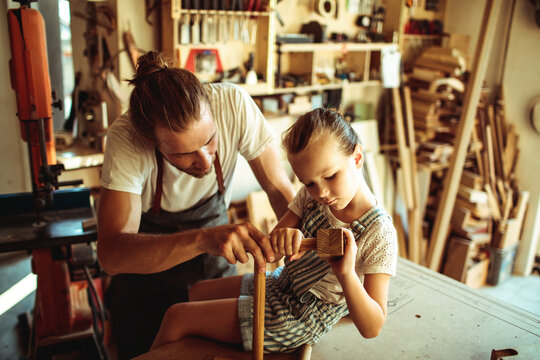 Father teaching daughter woodworking in home workshop