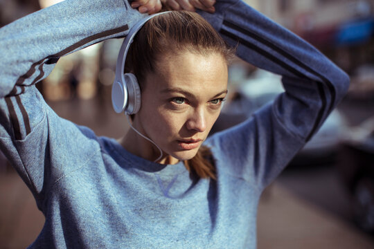 Focused woman athlete wearing headphones on city street