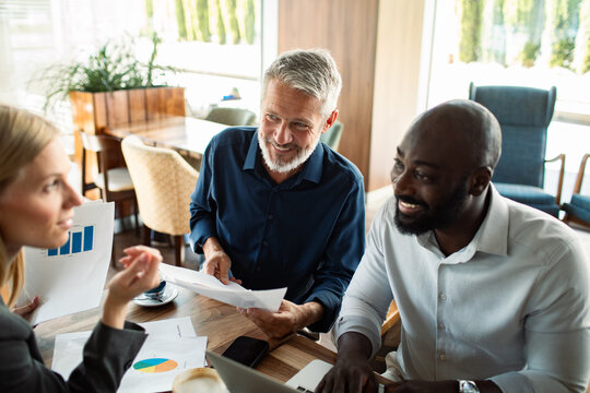 Coworkers discussing charts during casual meeting in cafe