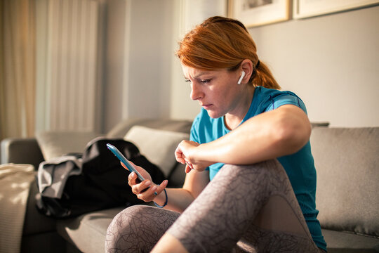 Young woman using smartphone after workout at home