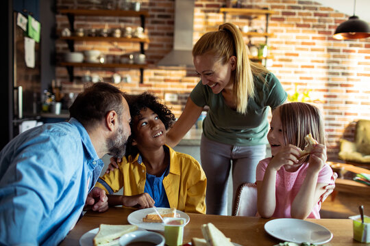 Parents and children enjoying breakfast together at home kitchen table