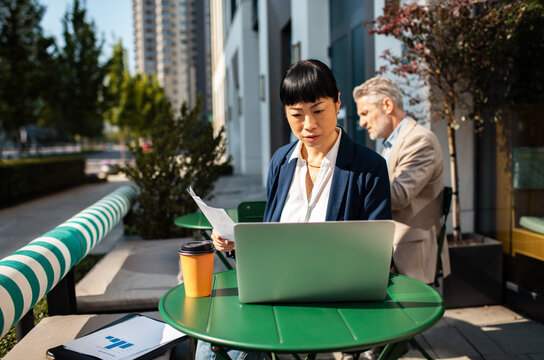 Businesswoman working on laptop at outdoor cafe in city