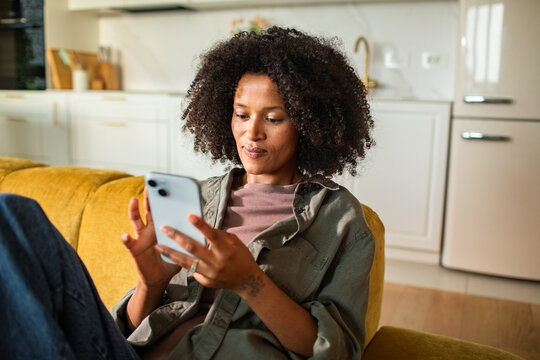 Relaxed woman using smartphone on home sofa