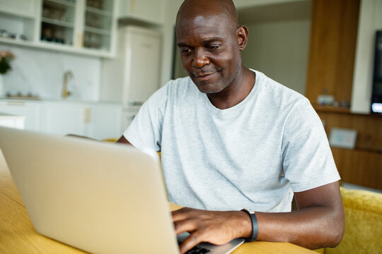 Mature man working on laptop at home kitchen table