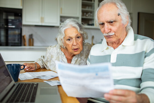 Senior couple reviewing bills at kitchen table