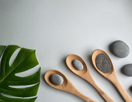wooden spoons and gray stones on light background with green leaf