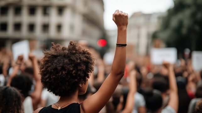 A diverse group of activists demonstrate unity in an urban setting. Raised fists and expressive faces capture the spirit of activism and community solidarity.