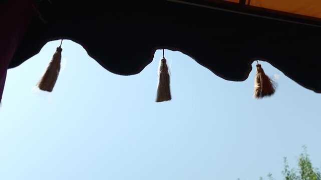 A black awning with colorful tassels hanging from it, suitable for use in travel, festival or party scenes