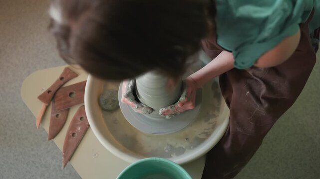 Woman transforms clay into vessel. Female potter meticulously shapes and refines her ceramic piece. An attentive female sculptor skillfully forms graceful bowl from malleable clay material