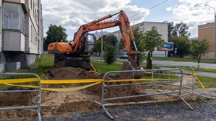Orange Heavy Excavator Digging Trench near Residential Building in City © yaviki