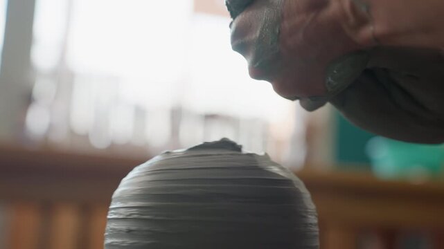 Demonstration of surface polishing. Artist softly smoothing ceramic edge under studio lighting. Pottery instructor illustrating delicate surface finishing process in calm studio environment