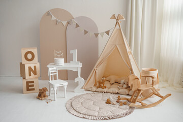 Boho first birthday photo zone with beige teepee, wooden rocking horse and white cake table © Minakryn Ruslan 