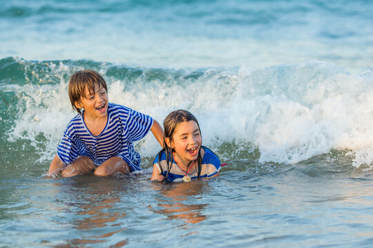 Two happy children in casual clothing playing in the surf on a summer day, Bulgaria