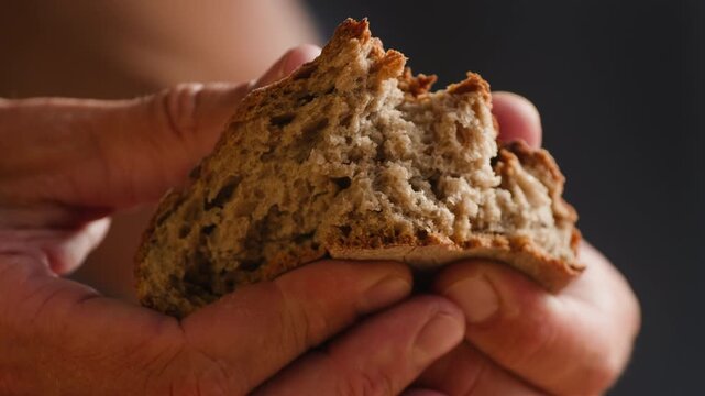 Bread multigrain loaf held in hands, whole wheat seeded crust with millet and seeds, close-up macro shot