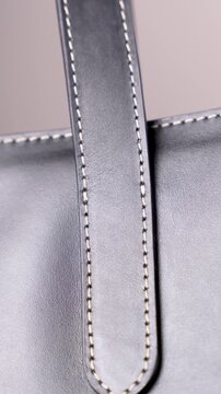 Macro shot showing the high-quality stitching on a black leather handbag strap and texture.