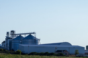 Farm Buildings Stand in Clear Skies Near a Rural Area During Daylight Hours With Storage Silos and a Large Warehouse Visible © Роман Булатов