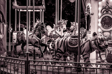Vintage-style black and white carousel horses and tiger figure at night. © Khalil