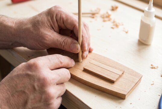 Inserting a wooden dowel mast into the deck of a handmade scale model boat