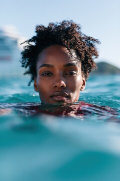 Close up portrait of a woman half submerged in ocean water for travel swim lifestyle banner and background use