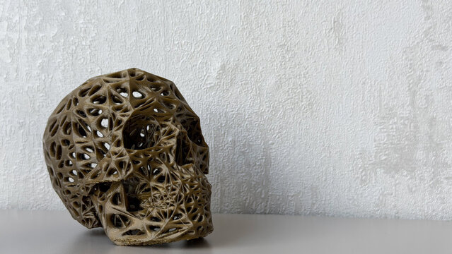 Abstract decorative skull sculpture with intricate openwork structure on a neutral textured background, modern artistic home decor with copy space.