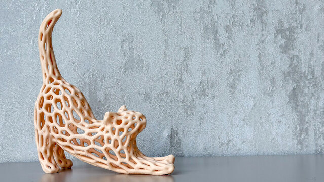 Abstract openwork cat sculpture in a stretching pose against a textured gray wall, modern decorative home accessory with generous copy space.