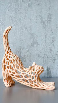 Abstract openwork cat sculpture in a stretching pose against a textured gray wall, modern decorative home accessory with generous copy space.