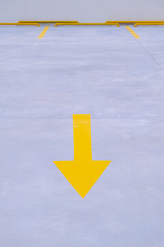 Minimalist top view of yellow arrow painted on asphalt floor pointing direction