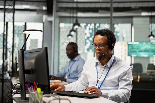 Helpdesk engineer speaks through a headset during a remote support call, responding to service alerts and helping users diagnose and resolve technical errors.