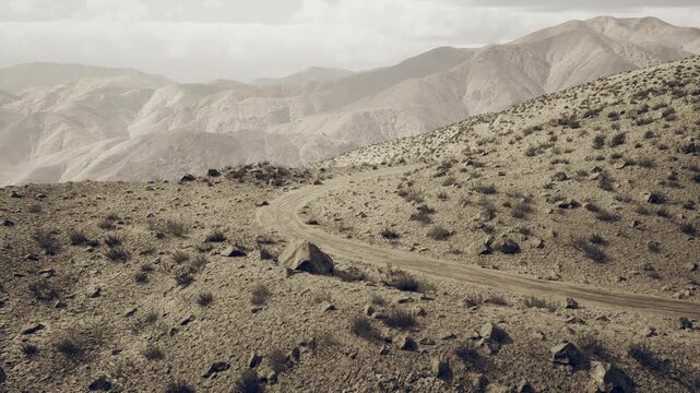 Layered mountain horizons in Uzbekistan form contemplative panorama with soft haze and receding ridgelines distant peaks, gentle slopes and muted tones suggest