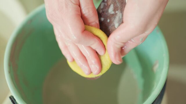 Artisan rinsing wooden rib in green basin, closeup of hands and sponge. Studio scene of final inspection after cleaning, water droplets, smooth grain, readiness for next throw, quiet satisfaction