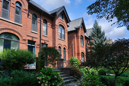 Old urban brick semi-detached houses with shady front yards with trees and bushes