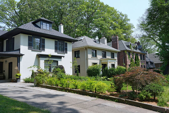 street of two story detached houses with large front yards and mature trees