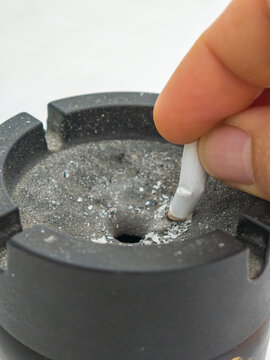 Hand Putting Out a Lighted Cigarette in a Black Ashtray