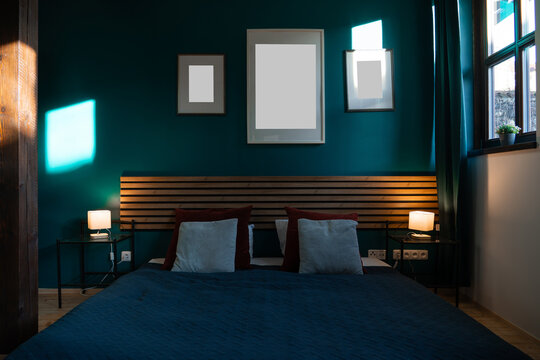 Three blank frames above bed in dark teal bedroom