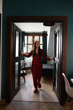 Smiling woman in plaid pajamas walking through doorway
