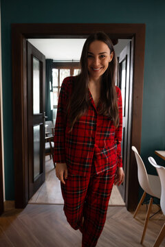 Smiling woman in plaid pajamas standing in doorway