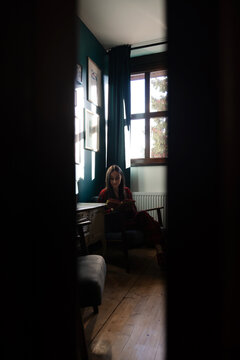 Woman reading a book through doorway in quiet room