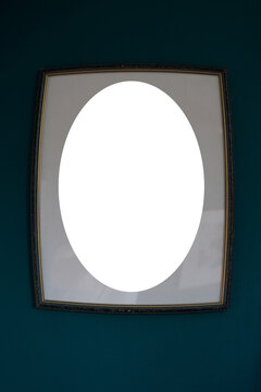 Empty vintage oval picture frame on dark teal wall