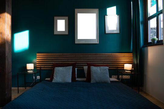 Three blank frames above bed in dark teal bedroom