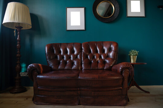 Vintage sofa against teal wall with blank frames