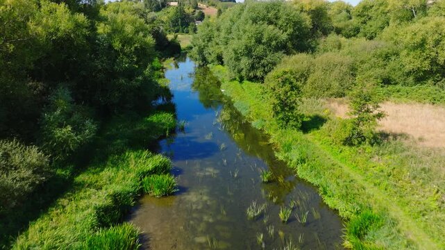 Drone shot flying along and downstream the River Avon in the Woodford Valley on a summer day. Wiltshire UK