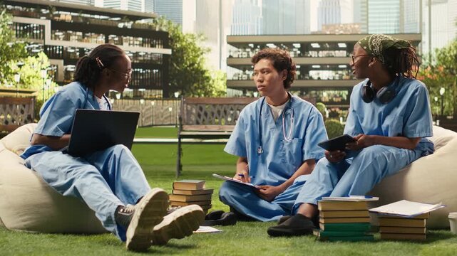 Medical students collaborate around a laptop and case study notes, writing in a notebook, as the study group combines peer tutoring and digital learning on an international campus.