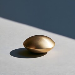Fototapeta premium Single brass paperweight centered on a soft gray background with harsh diagonal shadow