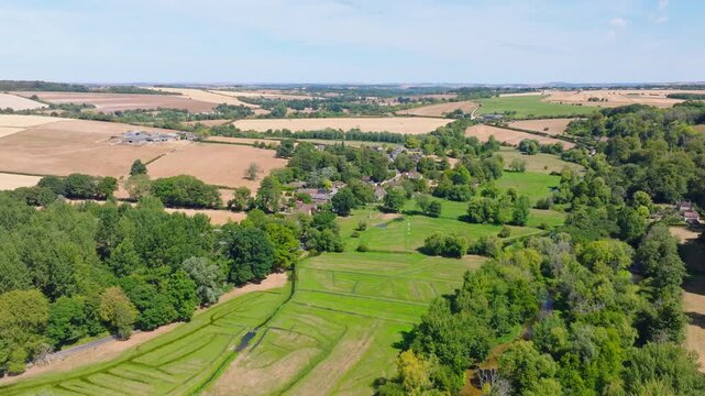 Aerial shot flying over the Woodford Valley towards Lower Woodford Village in summer, Wiltshire, UK