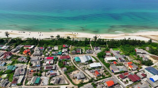 Aerial view of peaceful coastal fishing village with turquoise sea and white sand beach in Quang Tri Vietnam