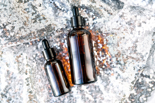 Skincare serum dropper bottles on sparkling glitter fabric